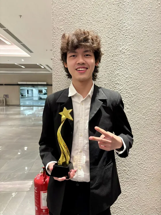 Aiden smiling in a black blazer, holding a star-shaped trophy